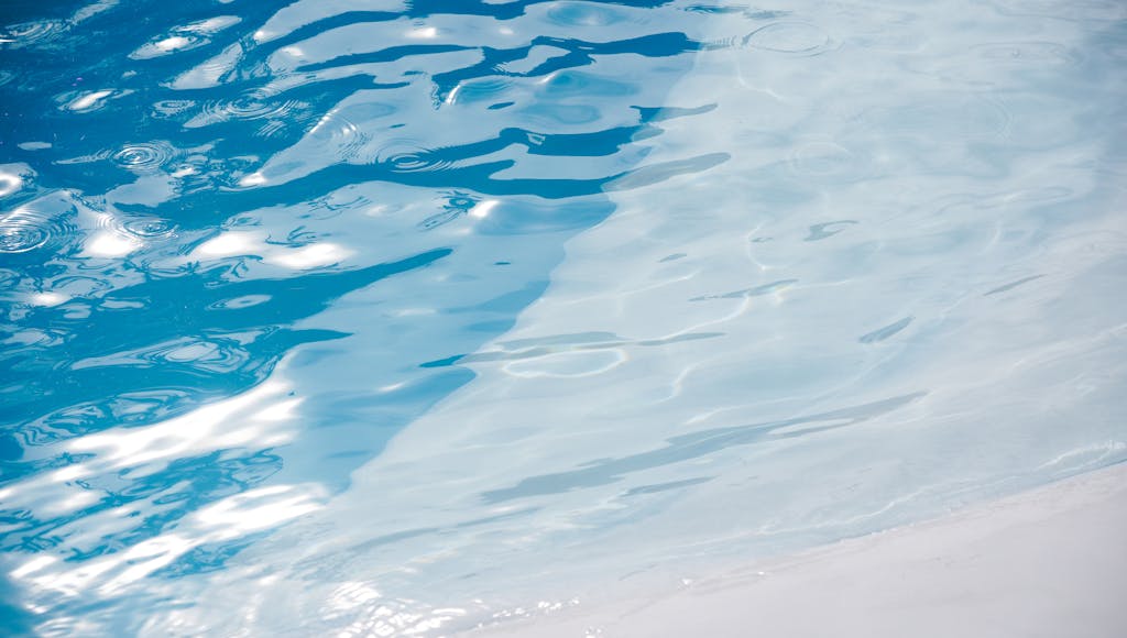Glistening blue pool water with sunlit ripples creating a serene and refreshing ambiance.